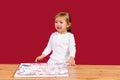 Little girl crying sitting at the wooden table with canvas picture set. Unpatient toddler girl waiting her mummy come to