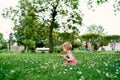 Little girl with a cucumber in her hand sits in a flower meadow. Side view