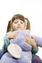 Little girl cuddling a stuffed elephant.