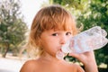 The little girl with curly golden hair pleasure drinks water fro Royalty Free Stock Photo