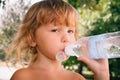 The little girl with curly golden hair pleasure drinks water fro Royalty Free Stock Photo