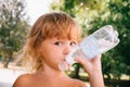 The little girl with curly golden hair pleasure drinks water fro Royalty Free Stock Photo