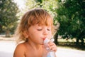 The little girl with curly golden hair pleasure drinks water fro Royalty Free Stock Photo