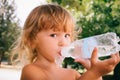 The little girl with curly golden hair pleasure drinks water fro Royalty Free Stock Photo