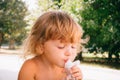 The little girl with curly golden hair pleasure drinks water fro Royalty Free Stock Photo