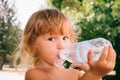 The little girl with curly golden hair pleasure drinks water fro Royalty Free Stock Photo