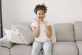 Girl sitting on couch and listening to music on headphones