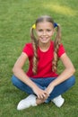 Little girl cute ponytails hairstyle relaxing on green grass, carefree childhood concept