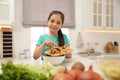 Little girl with cutting board and knife scraping vegetable peels into bowl