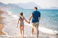 Little girl, dad, father walking on beach, sea ocean shore in sun protection swimsuit. Playing in sand, blue waves Royalty Free Stock Photo