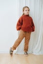 Little girl in dark orange knitted sweater, brown jeans and leopard sandals Royalty Free Stock Photo