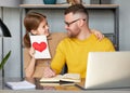 Little girl daughter making surprise for dad on Father`s Day and giving him handmade postcard with drawn heart Royalty Free Stock Photo