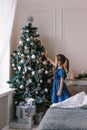 A little girl decorates the Christmas tree with toys and trinkets. Cute baby is getting ready to go home to celebrate Royalty Free Stock Photo