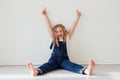 Beautiful little girl in denim jumpsuit played in white room