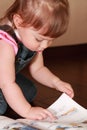 Little girl in denim jumpsuit reads book