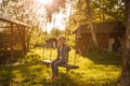 A little girl in a denim suit swings on a suspended swing to a tree. Royalty Free Stock Photo