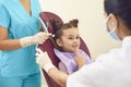 Little girl in a dental office shows two female dentists a tooth that worries her. Royalty Free Stock Photo