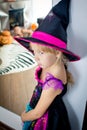 The little girl disguised as the witch is standing near a mirror