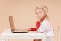 Little girl doctor sits at a laptop as a doctor and looks into the camera