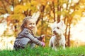 Little girl with dog in autumn park. Cute smiling girl having fun in walking with her pet. Happy child resting with dog outdoors. Royalty Free Stock Photo