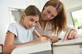 Little girl doing homework with her mother helping her