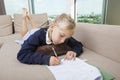 Little girl doing mathematics homework on sofa Royalty Free Stock Photo