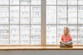 Cute 3-4 years old girl sitting in lotus pose with crossed legs on windowsill Royalty Free Stock Photo