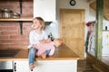 Little girl with doll sitting on kitchen countertop