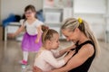 Little girl with down syndrome cuddling with her mother during ballet class. Concept of integration disabled children Royalty Free Stock Photo