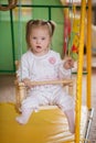 Little Girl with Down syndrome is riding on a swing