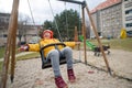 Happy little girl with Down syndrome on swing outdoors in playgraound.