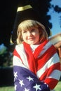 A little girl draped in an American flag,