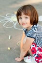 Little girl drawing on the asphalt close-up