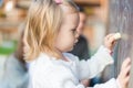 Little girl drawing on blackboard. Toddler girl having fun outdoors, holding chalk and drawing. Royalty Free Stock Photo