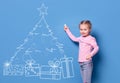 Little girl drawing christmas tree on wall