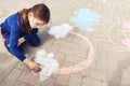 Little girl drawing a rainbow with chalk on paving Royalty Free Stock Photo