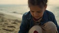 Little girl drawing sand on sea beach. Cute kid playing game on ocean coast.