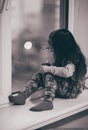 Little girl drawing on window glass at home