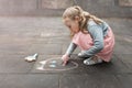 Little girl draws chalk on asphalt