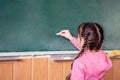 Little girl draws with chalk on a blackboard. The child performs a learning task. Babe starts school in first grade. School Royalty Free Stock Photo