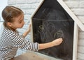 Cute little girl draws with chalk on the blackboard Royalty Free Stock Photo