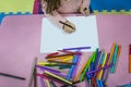 Little girl draws in a children`s center, garden and school on a white sheet. Royalty Free Stock Photo