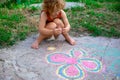 Little girl draws a flower on the pavement, creativity of children