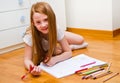 A little girl draws while lies on floor. Royalty Free Stock Photo