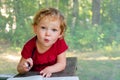 Little girl draws in a notebook on a background of nature. The beautiful, emotional face of a child of three years