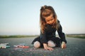 Little girl draws pictures on asphalt