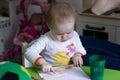 Little girl draws sitting at green table in kindergarten