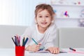 Little girl draws sitting at the table.