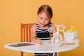 Little girl draws on a white table with crayons. Creative child. Studio photo on a yellow background. Art Royalty Free Stock Photo