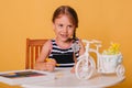 Little girl draws on a white table with crayons. Creative child. Studio photo on a yellow background. Art Royalty Free Stock Photo